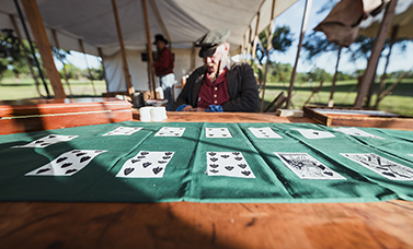 A cloth showing cards is laid out on a table in a tent, with a reenactor behind it.