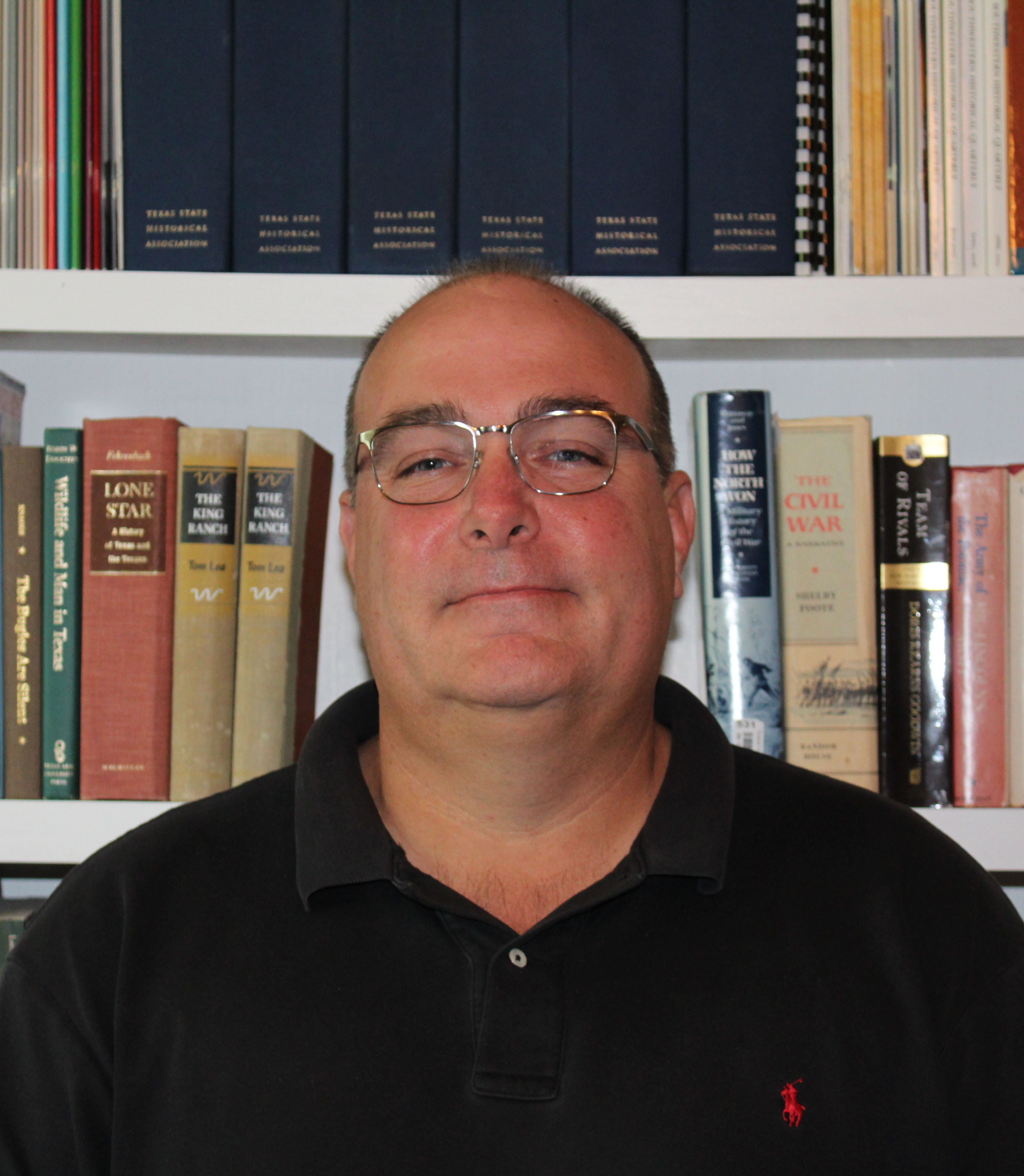Head and shoulders photo of Stephen Cure, in front of bookshelves