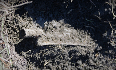 A magnifying glass inspecting a tool encrusted with dirt.