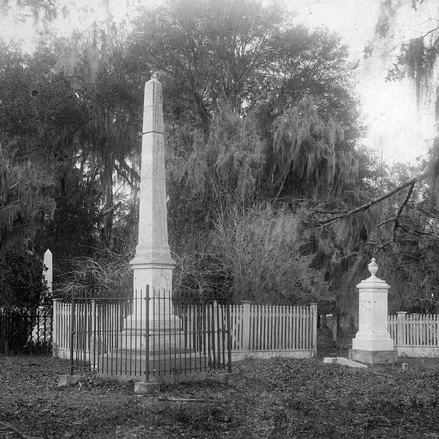 Balck and white photo of grave markers surrounded by a fence,