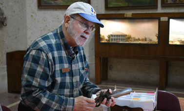 A docent talks about a 19th-century style handgun that he holds in his hands.