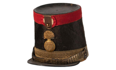 a tall cylindrical military hat with a red ribbon and gold emblem.