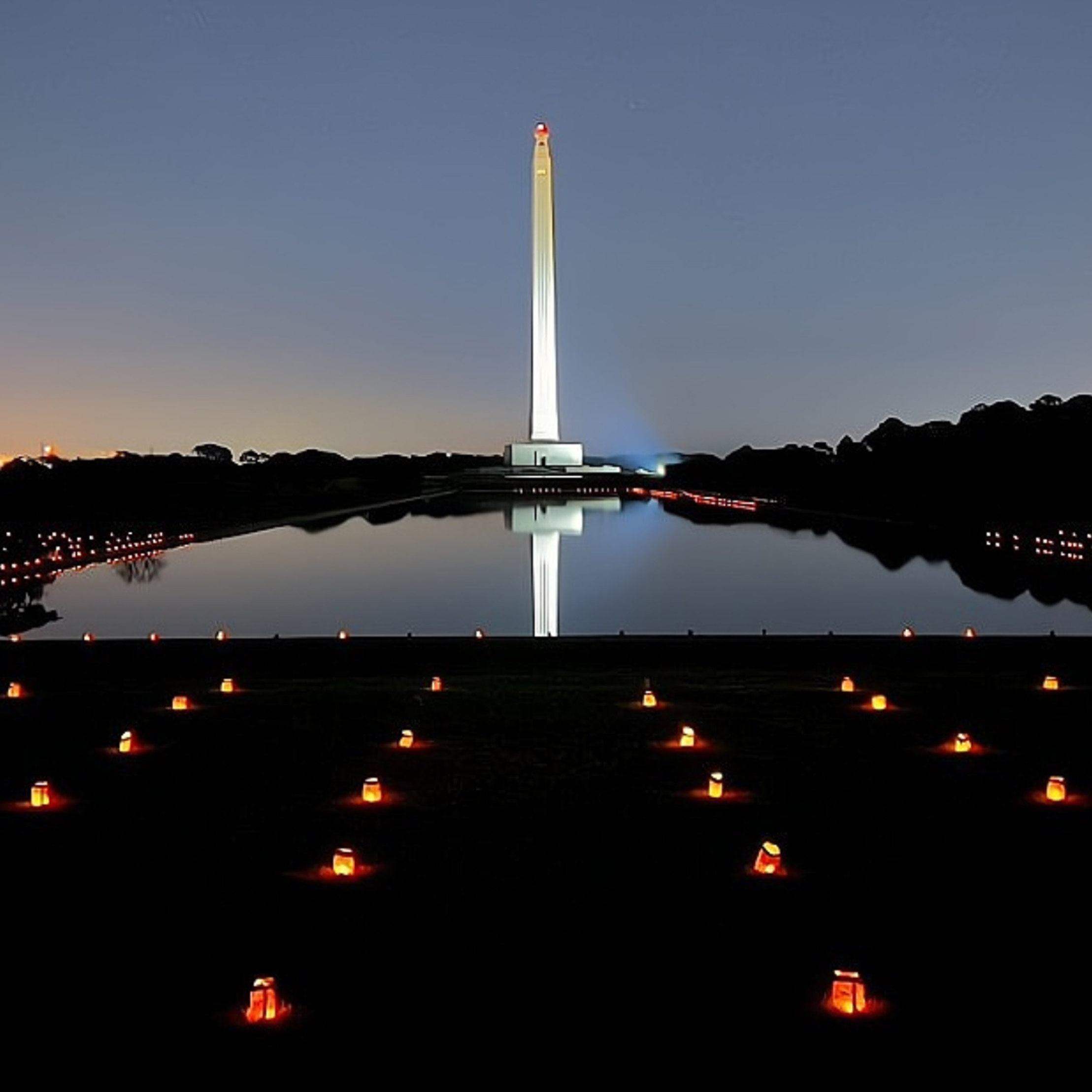 Luminaries line the sides of the Revlection pool, with the San Jacinto Monument in the background.