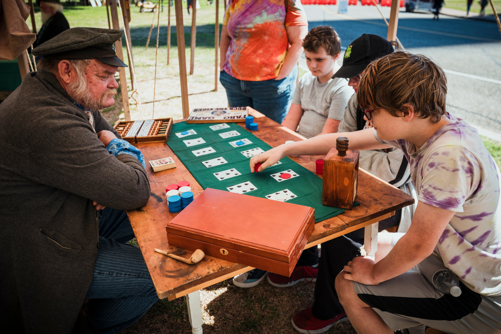 Three children play a card game with a reenactor.